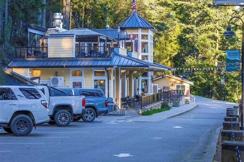 Slide: The Image of Pleasant Harbor Marina building with parked vehicles, surrounded by lush greenery and forest. - 48
