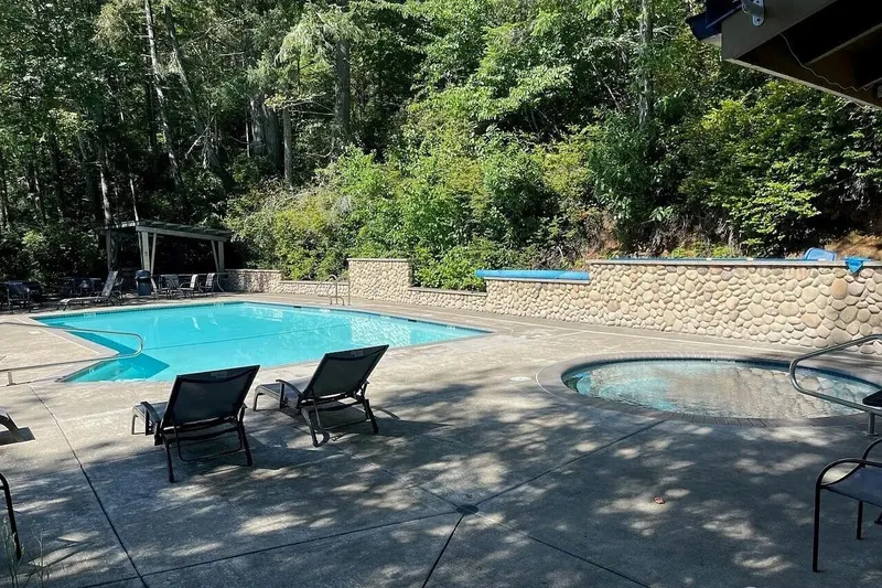 Slide: The Image of Outdoor pool and hot tub surrounded by lush greenery and lounge chairs. - 51