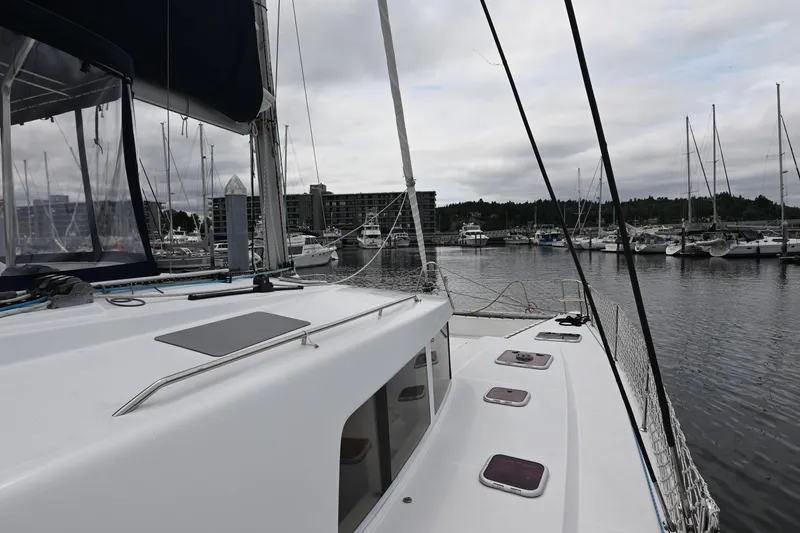 Slide: The Image of 2009 Lagoon 440 catamaran docked in a marina with sailboats and cloudy sky. - 13