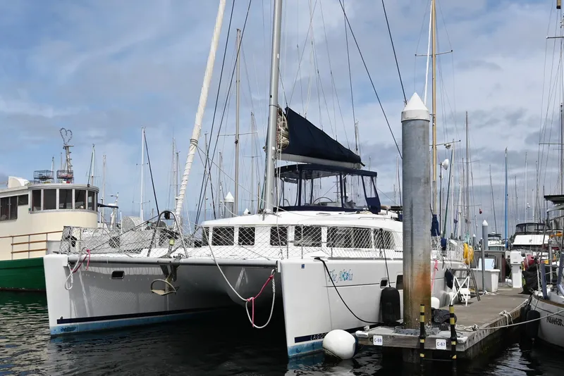 Slide: The Image of 2009 Lagoon 440 catamaran docked at a marina under a cloudy sky. - 3