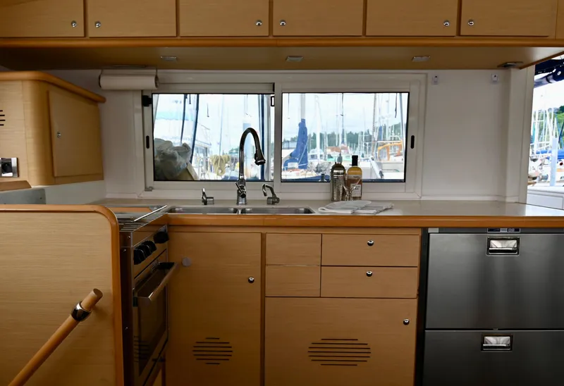 Slide: The Image of Interior of 2009 Lagoon 440 yacht kitchen with wooden cabinets and marina view. - 30