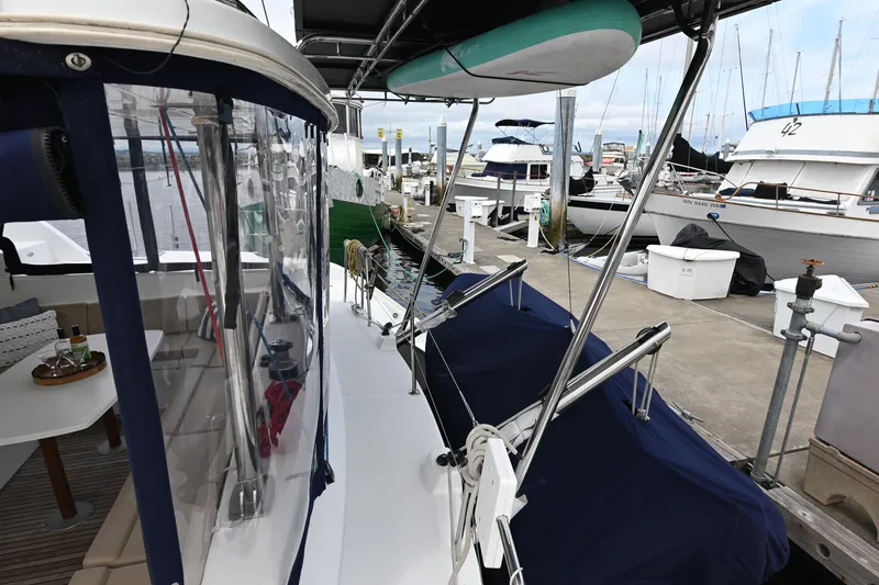 Slide: The Image of 2009 Lagoon 440 catamaran docked at marina, featuring covered seating and paddleboard storage. - 7