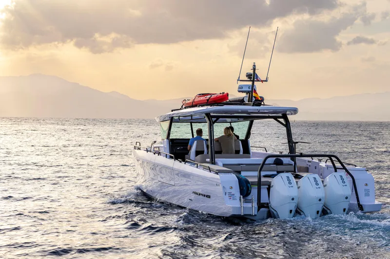 Slide: The Image of 2025 Axopar 45 Cross Top boat cruising on open water at sunset. - 10