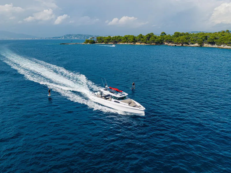 Slide: The Image of 2025 Axopar 45 Cross Top cruising on blue ocean near lush coastline. - 3