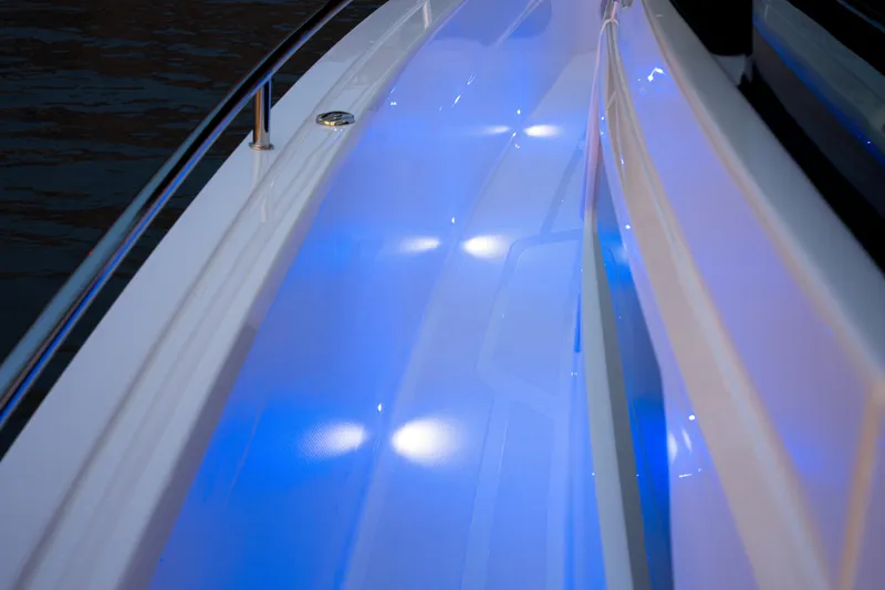 Slide: The Image of 2026 Axopar 45 Cross Top boat with illuminated blue deck lights at night. - 45