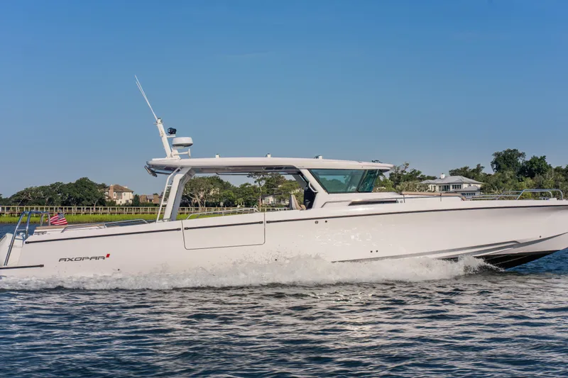 Slide: The Image of 2026 Axopar 45 Cross Top boat cruising on a sunny day, near a scenic shoreline. - 14
