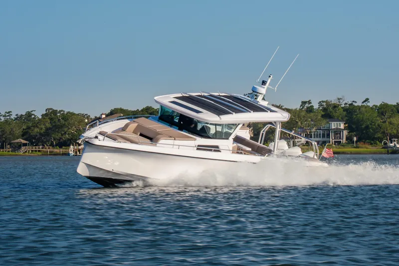 Slide: The Image of 2026 Axopar 45 Cross Top cruising on a scenic waterway, surrounded by lush greenery. - 1