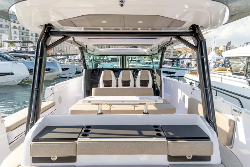 Slide: The Image of 2025 Axopar 45 Cross Top boat interior with seating and table, docked at marina. - 8