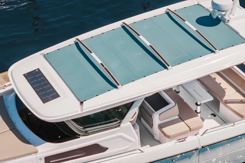 Slide: The Image of 2026 Axopar 45 Cross Top boat with teal canopy and solar panel, docked on water. - 17