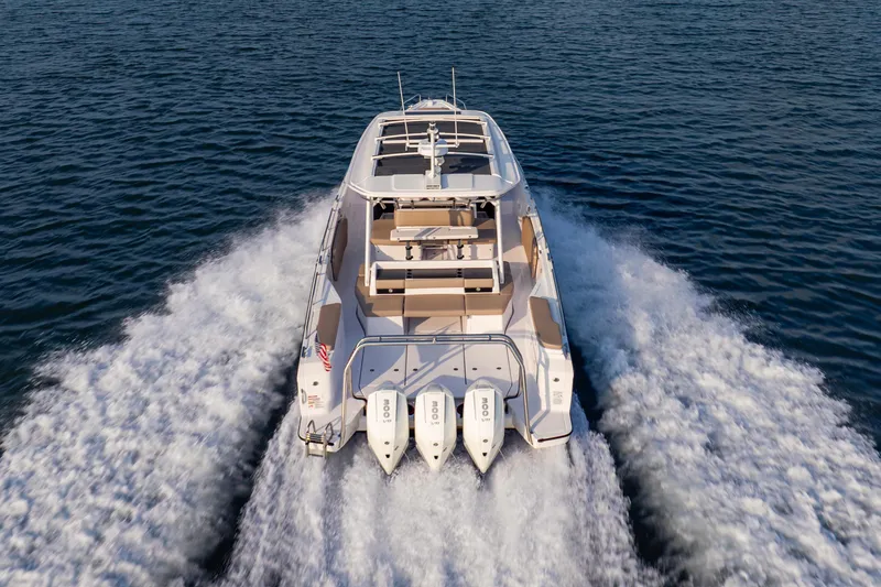 Slide: The Image of 2026 Axopar 45 Cross Top boat cruising on open water, rear view. - 8