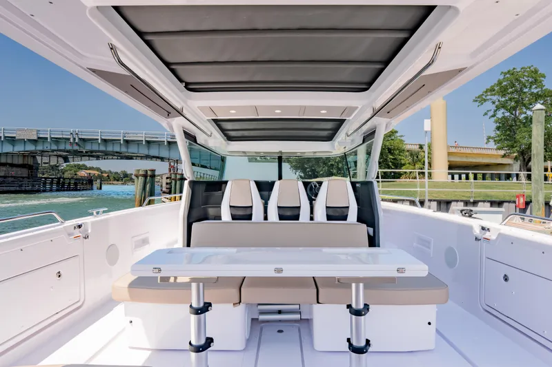Slide: The Image of 2026 Axopar 45 Cross Top boat interior with seating and table, near a bridge and waterway. - 28