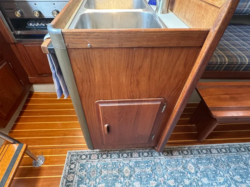 Slide: The Image of 1984 O'Day 34 Sloop interior with wooden cabinetry, double sink, and striped flooring. - 10