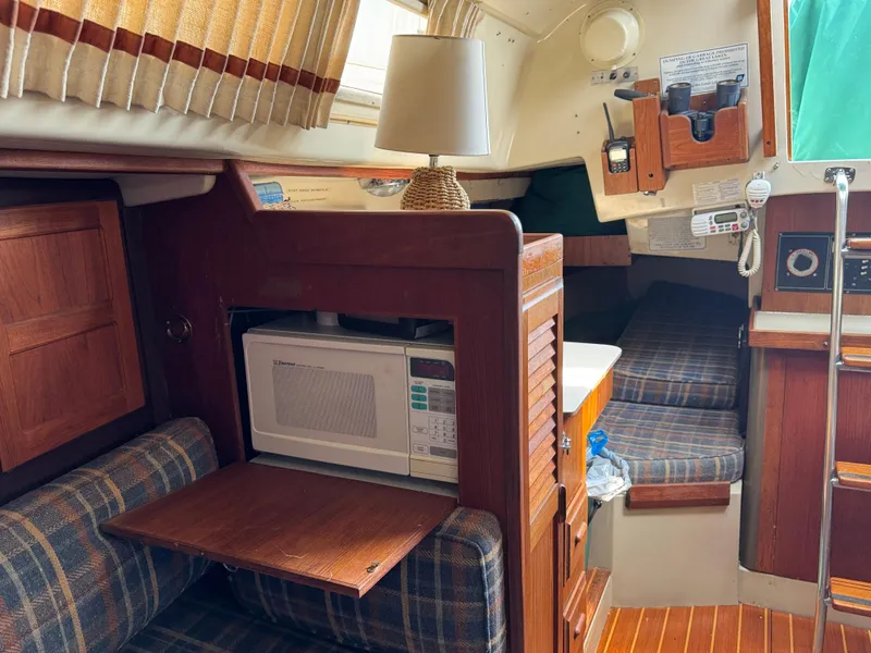 Slide: The Image of Interior of 1984 O'Day 34 Sloop with cozy seating, microwave, and nautical decor. - 12