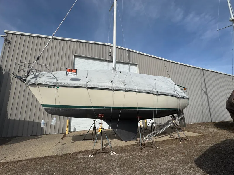 Slide: The Image of 1984 O'Day 34 Sloop sailboat on stands, covered, near a metal building. - 37