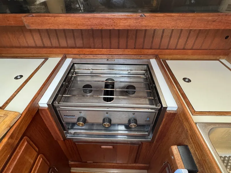 Slide: The Image of 1984 O'Day 34 Sloop yacht kitchen with a stainless steel stove and wooden cabinetry. - 8