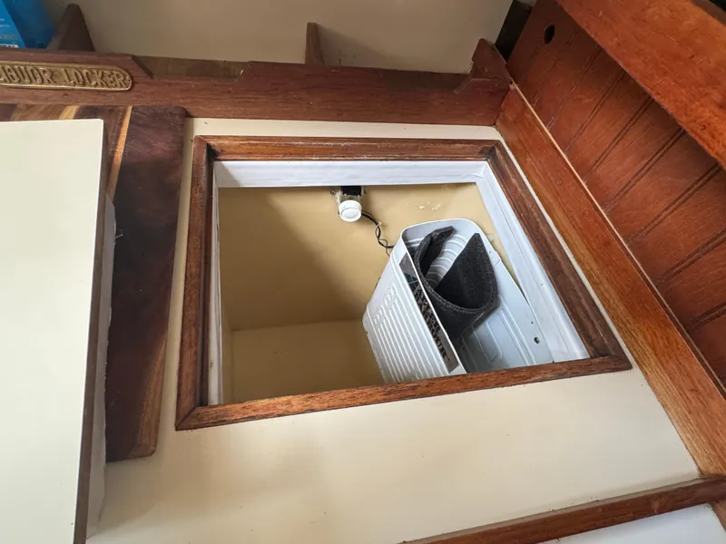 Slide: The Image of 1984 O'Day 34 Sloop interior storage compartment with wooden trim and equipment inside. - 9