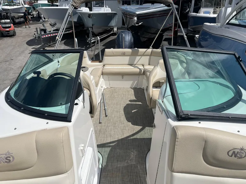 Slide: The Image of 2018 NauticStar 243DC Sport Deck boat interior with beige seating and dual windshields. - 12