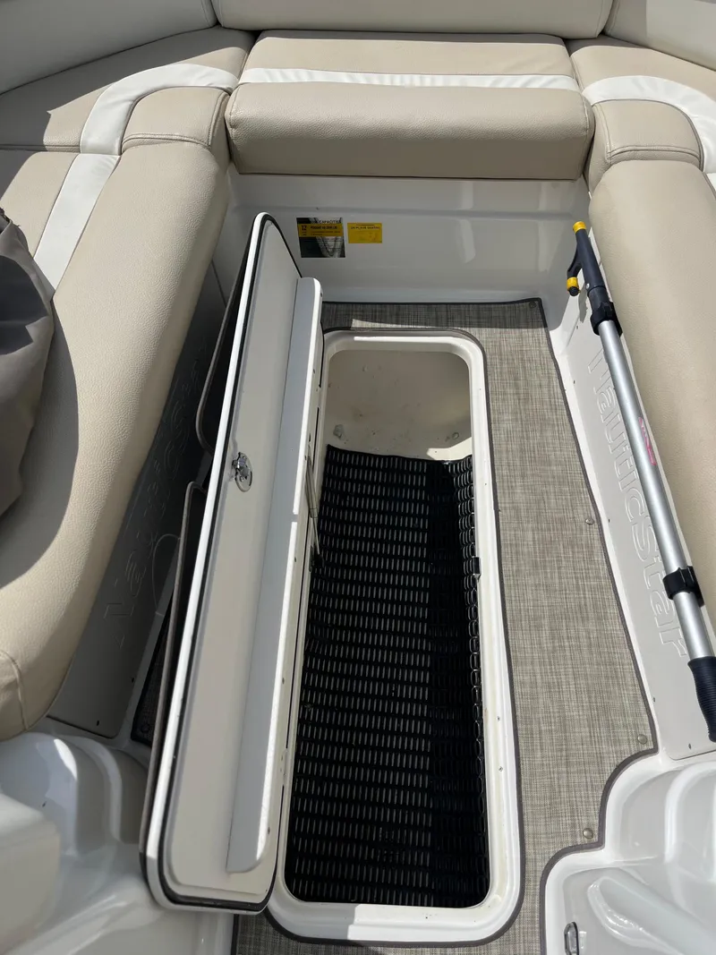 Slide: The Image of 2018 NauticStar 243DC Sport Deck interior with open storage compartment and seating. - 18