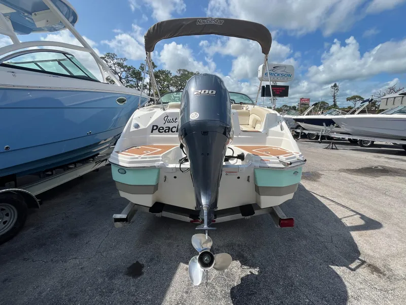 Slide: The Image of 2018 NauticStar 243DC Sport Deck boat with outboard motor, parked in marina under blue sky. - 2