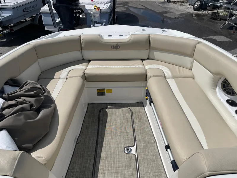 Slide: The Image of 2018 NauticStar 243DC Sport Deck boat with beige seating and spacious interior. - 7
