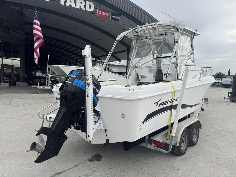 Slide: The Image of 2004 Pro-Line 22 Walk boat on trailer, displayed outdoors near a showroom. - 3
