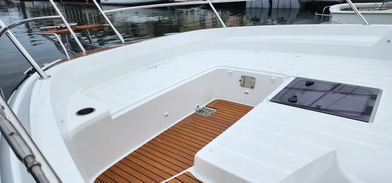Slide: The Image of 2022 Jeanneau Leader 12.5 WA boat deck with teak flooring and white seating. - 12