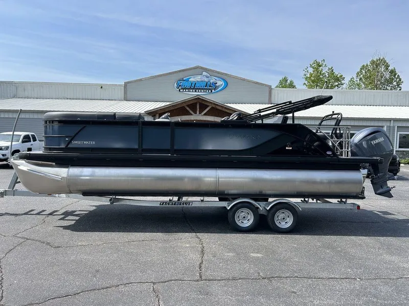 The Image of 2025 Godfrey Sweetwater 2286 SFLC pontoon boat on trailer, parked outside a marine center. - 1