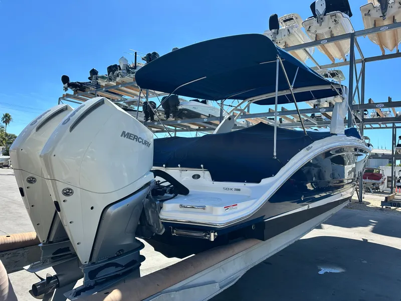 Slide: The Image of 2019 Sea Ray SDX 290 Outboard boat with dual Mercury engines, docked under a blue canopy. - 19