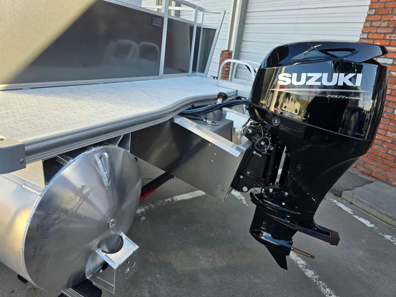 Slide: The Image of 2025 Berkshire 20 CL pontoon boat with Suzuki outboard motor, parked outdoors. - 2