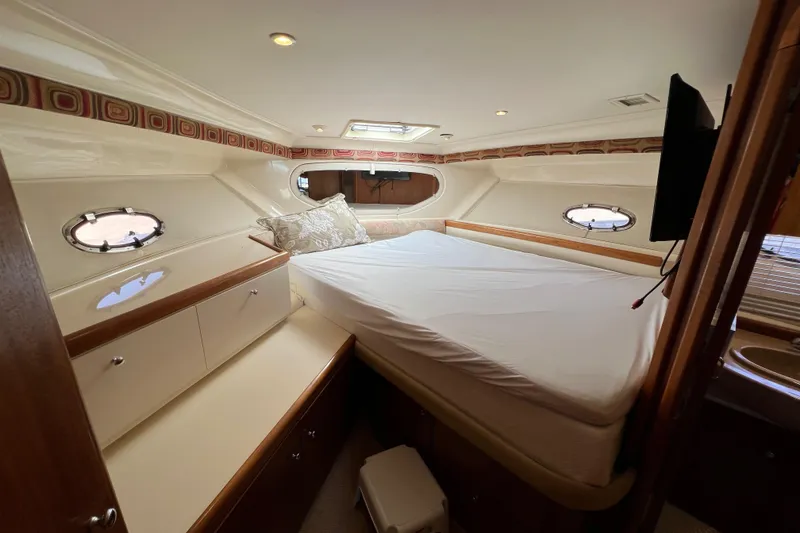 Slide: The Image of 1997 Carver 350 Mariner cabin interior with bed, portholes, and storage cabinets. - 24