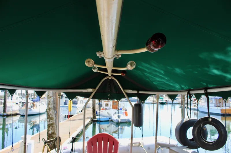 Slide: The Image of 1961 Custom 32' William Garden Tug with green canopy at marina, featuring nautical equipment. - 15