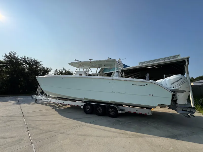 Slide: The Image of 2022 Invincible 40 Catamaran on trailer, parked outdoors under clear sky. - 17