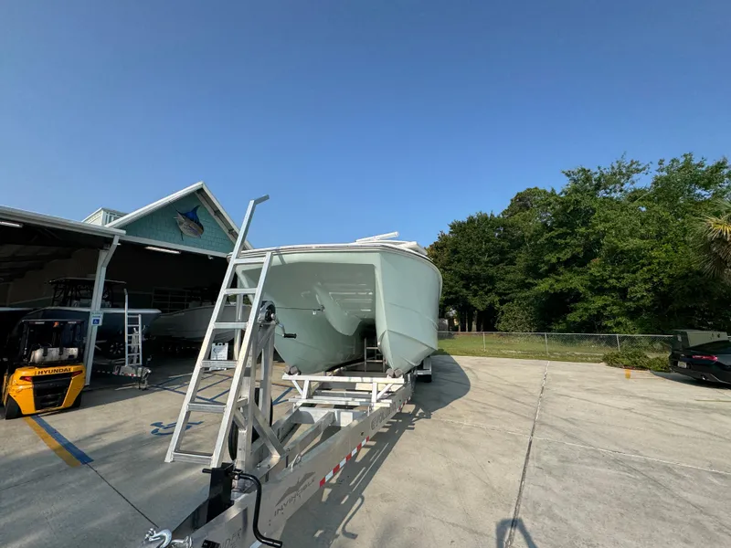 Slide: The Image of 2022 Invincible 40 Catamaran on trailer, parked outdoors near a building and trees. - 6