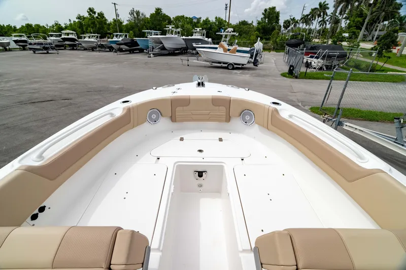 Slide: The Image of 2026 Edgewater 248 CX boat interior with beige seating, parked in a marina. - 43