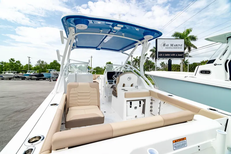 Slide: The Image of 2026 Edgewater 248 CX boat with beige seating and blue canopy in marina setting. - 6