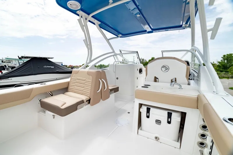 Slide: The Image of 2026 Edgewater 248 CX boat interior with seating, sink, and storage under a blue canopy. - 7