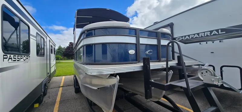 The Image of 2021 Crest Classic LX 220 SLC pontoon boat parked between RVs under a blue sky. - 1