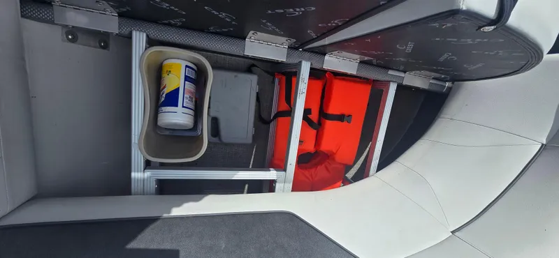 Slide: The Image of Storage compartment in 2021 Crest Classic LX 220 SLC boat with life jacket and cleaning supplies. - 11