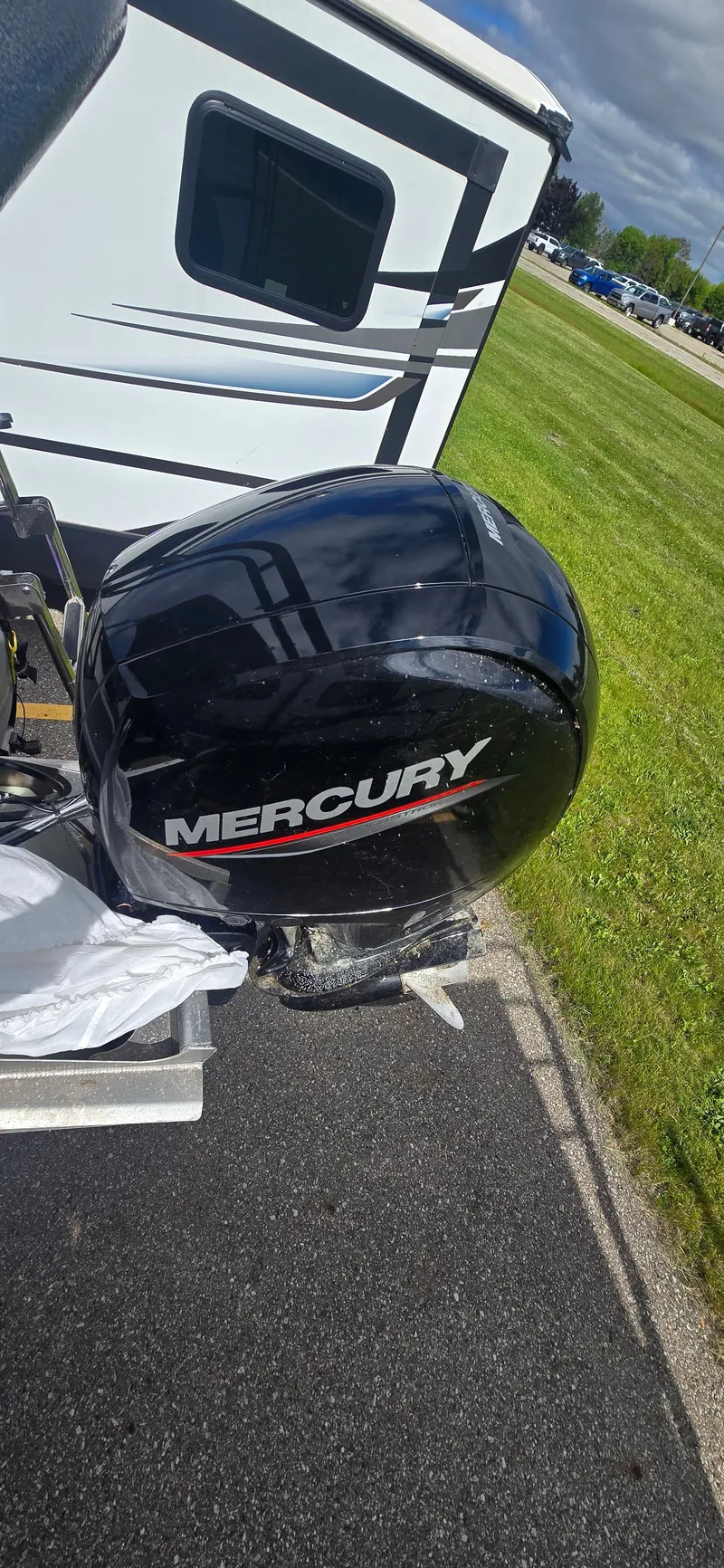 Slide: The Image of Outboard motor on a 2021 Crest Classic LX 220 SLC boat, parked near a grassy area. - 15