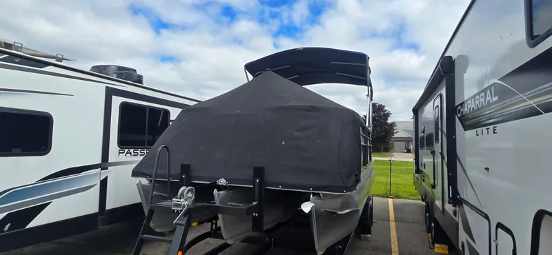 Slide: The Image of 2021 Crest Classic LX 220 SLC boat covered, parked between two RVs under cloudy sky. - 5