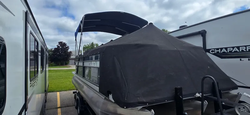 Slide: The Image of 2021 Crest Classic LX 220 SLC pontoon boat with cover, parked between RVs. - 6