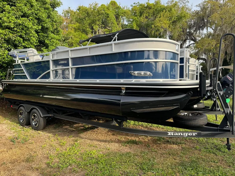 The Image of 2024 Ranger Reata 220C pontoon boat on trailer, parked outdoors. - 0
