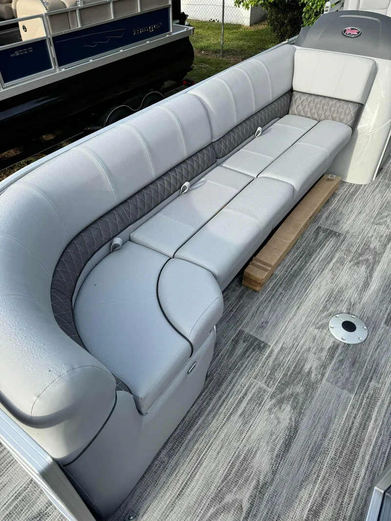 Slide: The Image of 2024 Ranger Reata 220C boat interior with gray cushioned seating and wood-style flooring. - 7