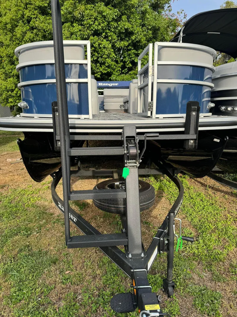 Slide: The Image of 2024 Ranger Reata 220C pontoon boat on trailer, parked on grass. - 8