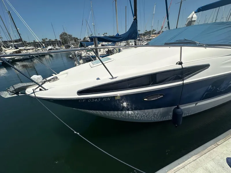 The Image of 2008 Bayliner 265 boat docked in a marina, surrounded by other sailboats. - 0