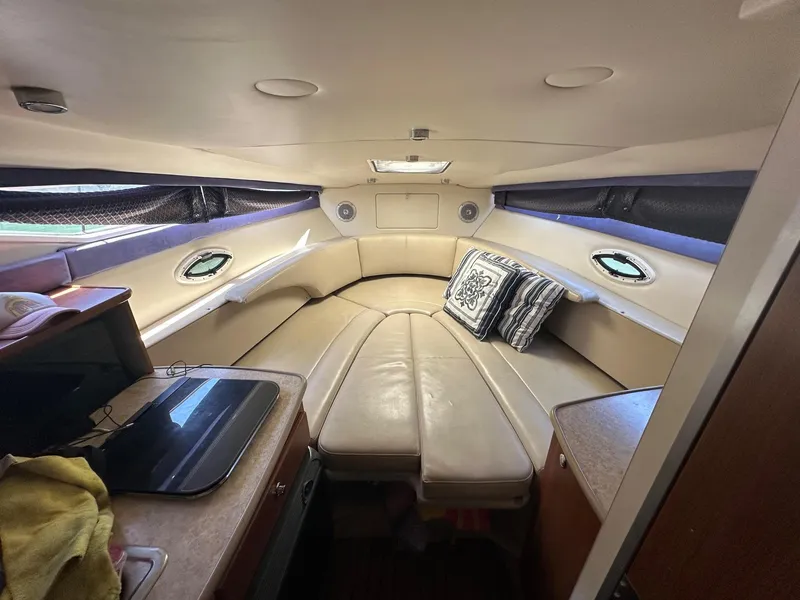 Slide: The Image of 2008 Bayliner 265 cabin interior with beige seating and a small table. - 8
