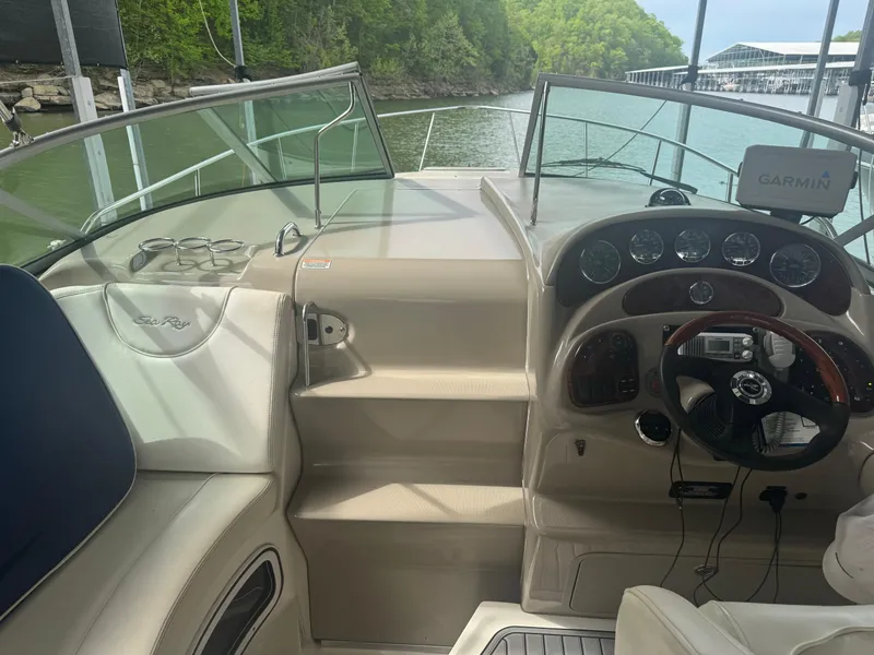 Slide: The Image of 2006 Sea Ray 280 Sundancer cockpit with steering wheel and navigation system, docked by a lake. - 8
