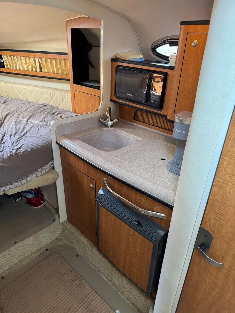 Slide: The Image of 2006 Sea Ray 280 Sundancer cabin with kitchenette, sink, and cozy sleeping area. - 9