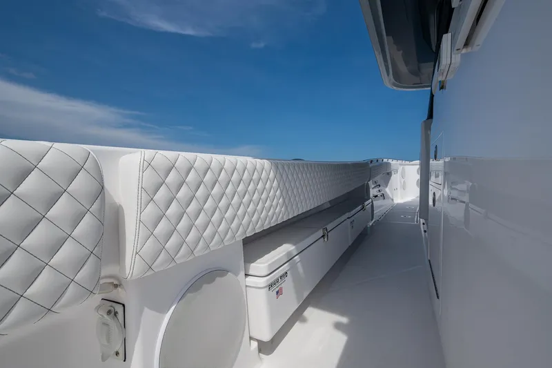 Slide: The Image of 2025 HCB 48 Campeon boat interior with quilted seating and sleek white design under blue sky. - 34
