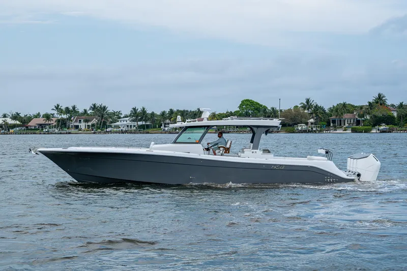 Slide: The Image of HCB 48 Campeon 2025 boat cruising on a calm waterway with houses in the background. - 7